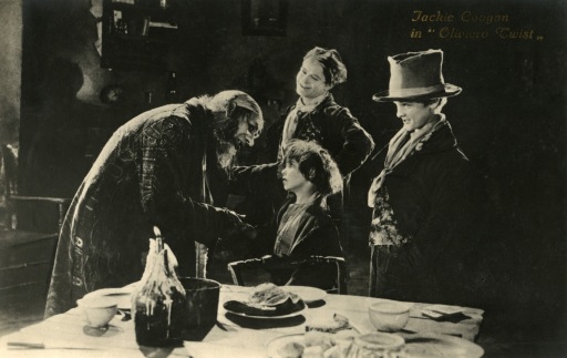 Picture of an evil man bothering an orphan while a woman looks on smiling, from the movie, "Oliver Twist."